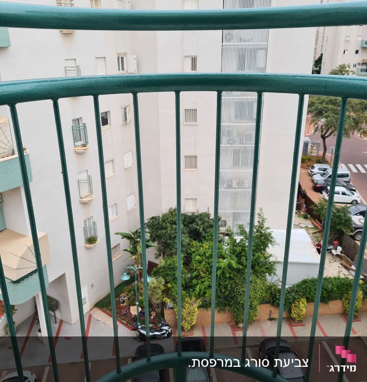 מעקה ירוק צבוע במרפסת בניין